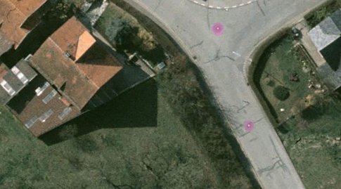 Auf einem Luftbild von einer Straße, Häusern und einem Feld sind zwei Punkte auf der Straße rosa markiert.