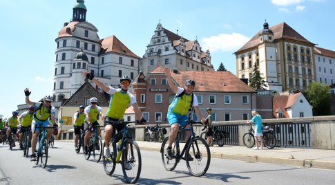 Mehrere Radler vor Stadtkulisse mit Schloss