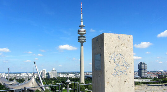 Geodätischer Referenzpunkt mit Olympiaturm im Hintergrund